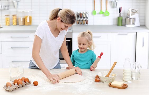 Young woman and her daughter cooking in kitchen