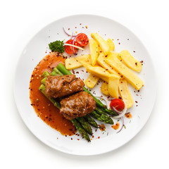 Wrapped pork chop with french fries and asparagus on white background