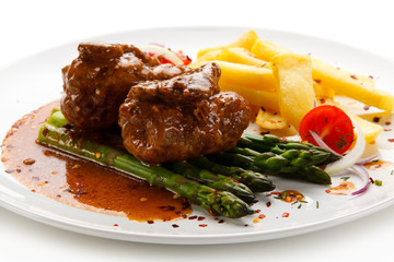 Wrapped pork chop with french fries and asparagus on white background