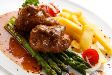 Wrapped pork chop with french fries and asparagus on white background