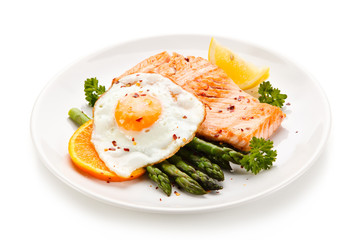 Griilled salmon with asparagus and fried egg on white background