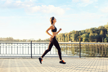 Woman running by the lake at sunset. Sport and lifestyle concept