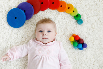 Fototapeta na wymiar Cute baby girl playing with colorful wooden rattle toy