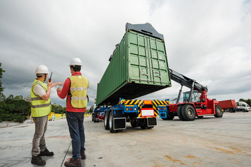 forklift lifting on the container to the trailer in yard, under foreman control in charge © ID_Anuphon