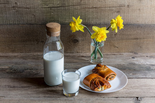 Glass and bottleof milk , biscuit and flowers on wood background