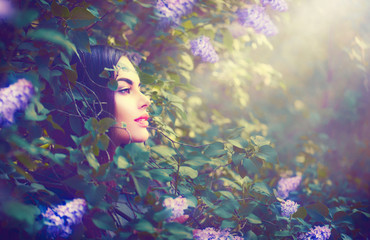 Fashion spring model girl portrait in lilac flowers fantasy garden