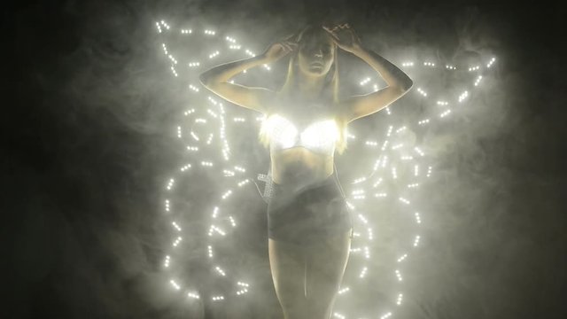Dancer performing in led costume butterfly wings in smoke on stage