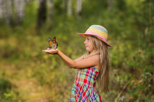 Butterfly sitting on the hand of a young girl in the forest