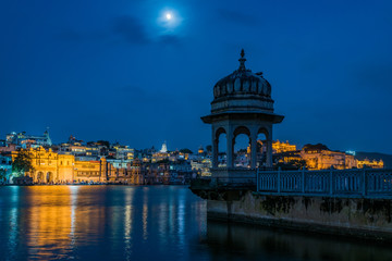 Fototapeta na wymiar Udaipur's Gangaur Ghat seen under the backdrop of a chattri and a moonlit night on the banks of Lake Pichola.