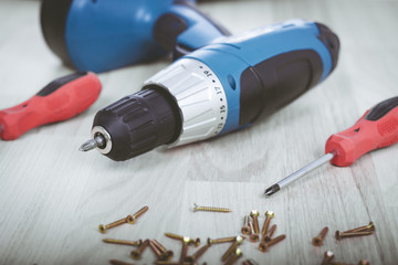 Carpenter screwing the crew with cordless screwdriver into wooden board