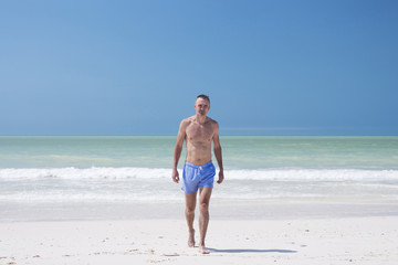 Fototapeta na wymiar Man is walking on the white beach of Cancun, Mexico