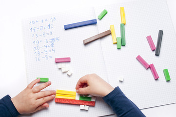 Open exercise book with colored plastic math learning tools number rods on white background....
