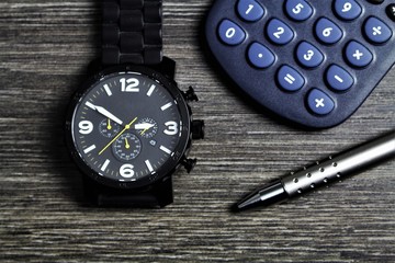 An image of a clock, pen and a calculator