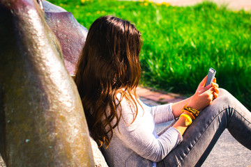Young beautiful girl in park with mobile phone.