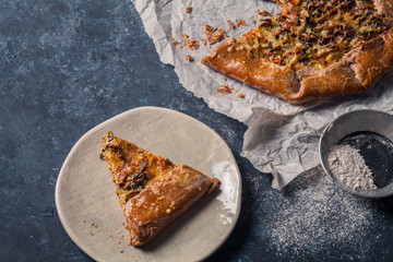 French styled leek and onion galette with sage and gruyere cheese made with wholegrain flour. Textured blue background. Rustic concept