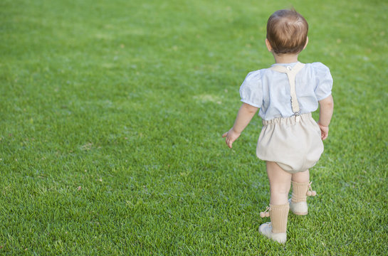 Little boy woth formal wear standing over green grass field