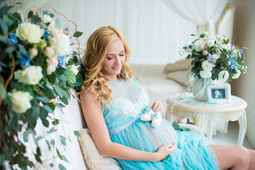 The most charming pregnant girl in a gentle interior with fresh flowers.