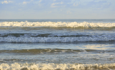 Wave running to the sand beach under blue sky