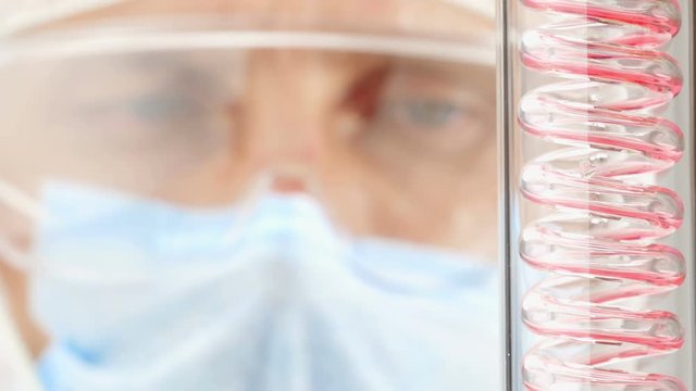 Scientist watching chemicals processing through a condenser in a lab.
