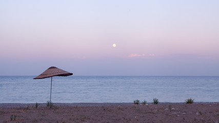 Seacoast with an umbrella from the sun at sunset in Turkey