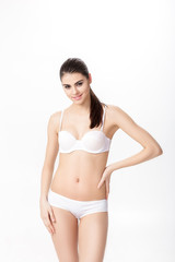 Obraz premium portrait of smiling young brunette woman with perfect sporty body in white underwear on white background