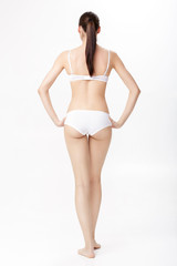 Fototapeta premium back view of beautiful young brunette woman with perfect sporty body in white lingerie on white background. 