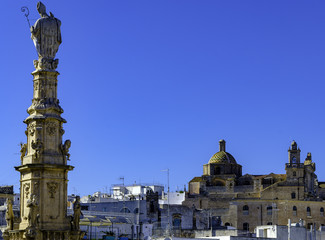 View on the Statue of San Oronzo and the Old Town of Ostuni, Puglia, Italy.
