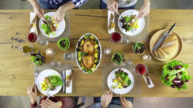 Overhead top view table four caucasian friends eating lunch and drinking together with chicken,sala, potatoes, red wine. in modern house home. 4k video