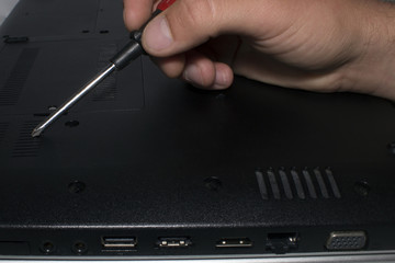 A man's hand lifted a screwdriver to disassemble the computer