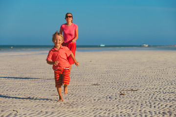 family beach vacation - little son and mother running at sea