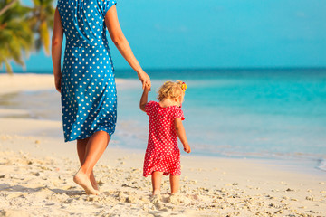 mother and little daughter walking on beach