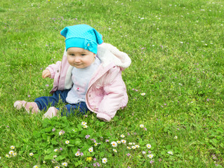 Little cute baby playing on the green flowering meadow