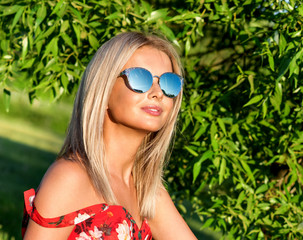 Outdoor fashion portrait of young pretty   blond woman in sunny day outdoor. Girl in sunglasses.