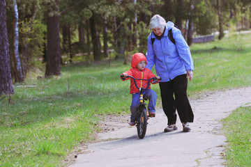 Fototapeta premium Grandmother teaching little granddaughter to ride bike