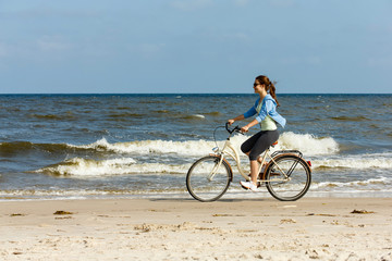 Teenage girl biking on beach