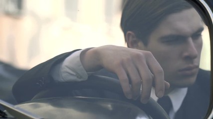 Pensive man in a 1920s suit sitting at the wheel, close-up shooting