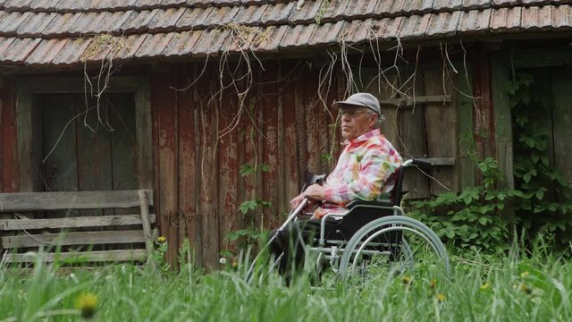 An elderly disabled man sitting in a wheelchair. Countryside