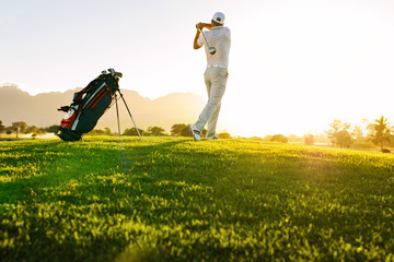 Professional golfer taking shot on golf course - obrazy, fototapety, plakaty
