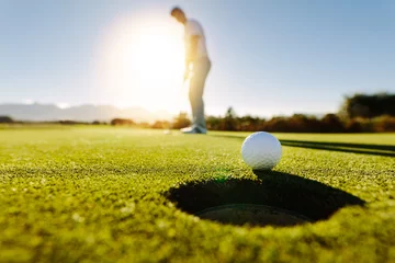 Foto op Plexiglas Golf Man zet de bal op golfbaan groen