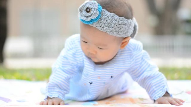 cute Asian baby lie prone on ground at park