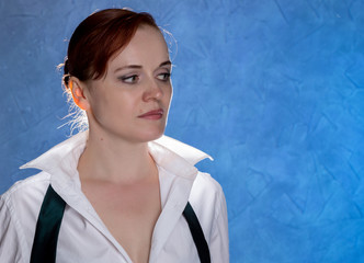 Beautiful sensual young woman in men's shirt and tie on a blue background