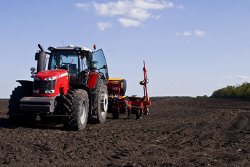 Obraz premium The tractor on the field in the spring plows the ground