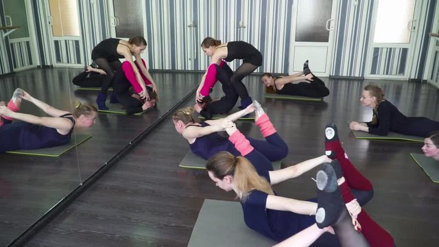 Trainer stretching women in front of the mirror