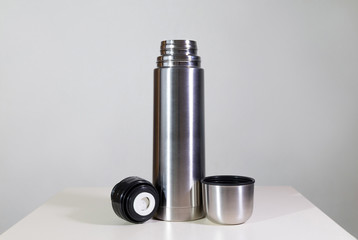 Metal vacuum flask.
Closeup of a stainless steel vacuum flask and its cup on white background.