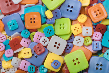 bright multicolored buttons of red, yellow, blue, orange, pink color, among them the white button - smiley stands out among other, top view, background