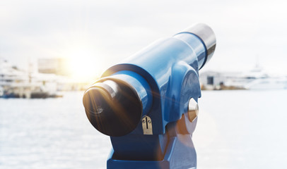Touristic telescope look at city and sea with sunset view of Barcelona Spain, close up blue binoculars on background viewpoint pier port yacht, coin operated in panorama observation sunrise 