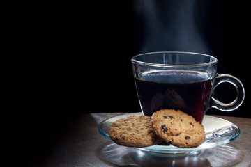 Steaming hot black coffee with chocolate chip cookies