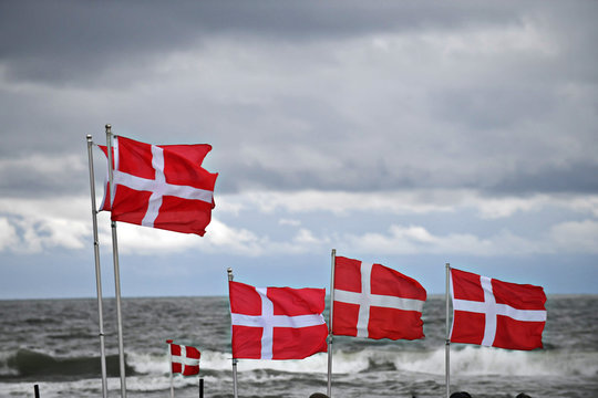 dänische Flaggen vor Meer und dunklen Wolken