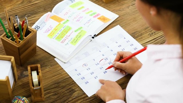 Businesswoman Circling A Date With Red Marker On Calendar