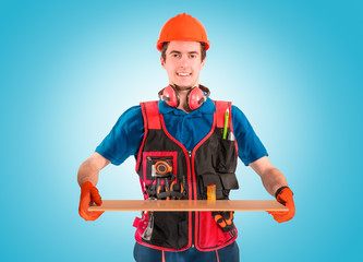 Handsome young handyman with a tool belt looking on a plate in hand. House renovation service. Building concept.